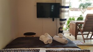 Une chambre avec un lit, un téléviseur fixé au mur, une chaise et une petite table.