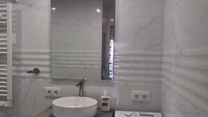 Une salle de bain avec un lavabo blanc, un miroir, un porte-serviettes et un meuble blanc.
