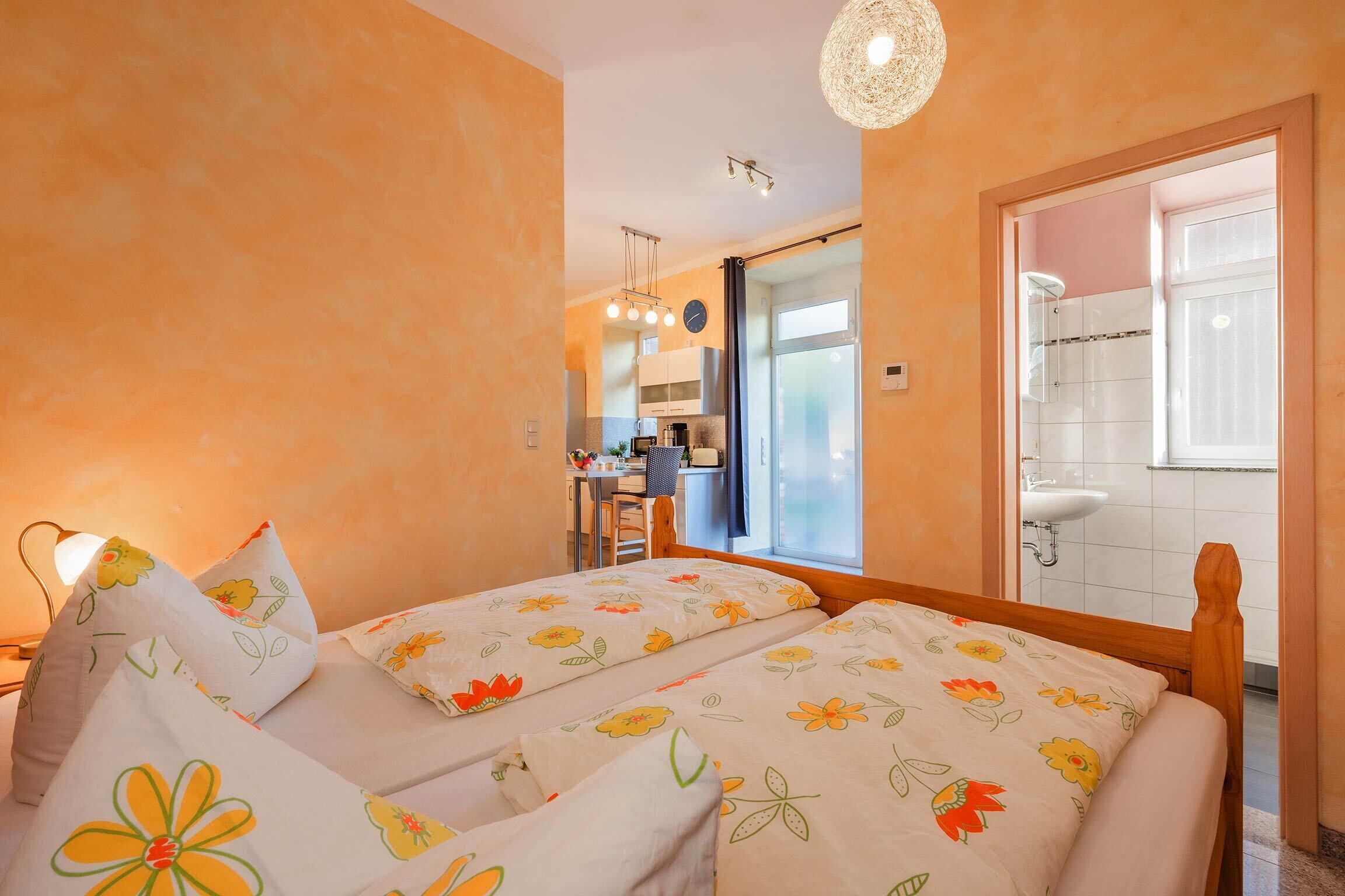Une chambre avec deux lits, un coin cuisine et une salle de bain.