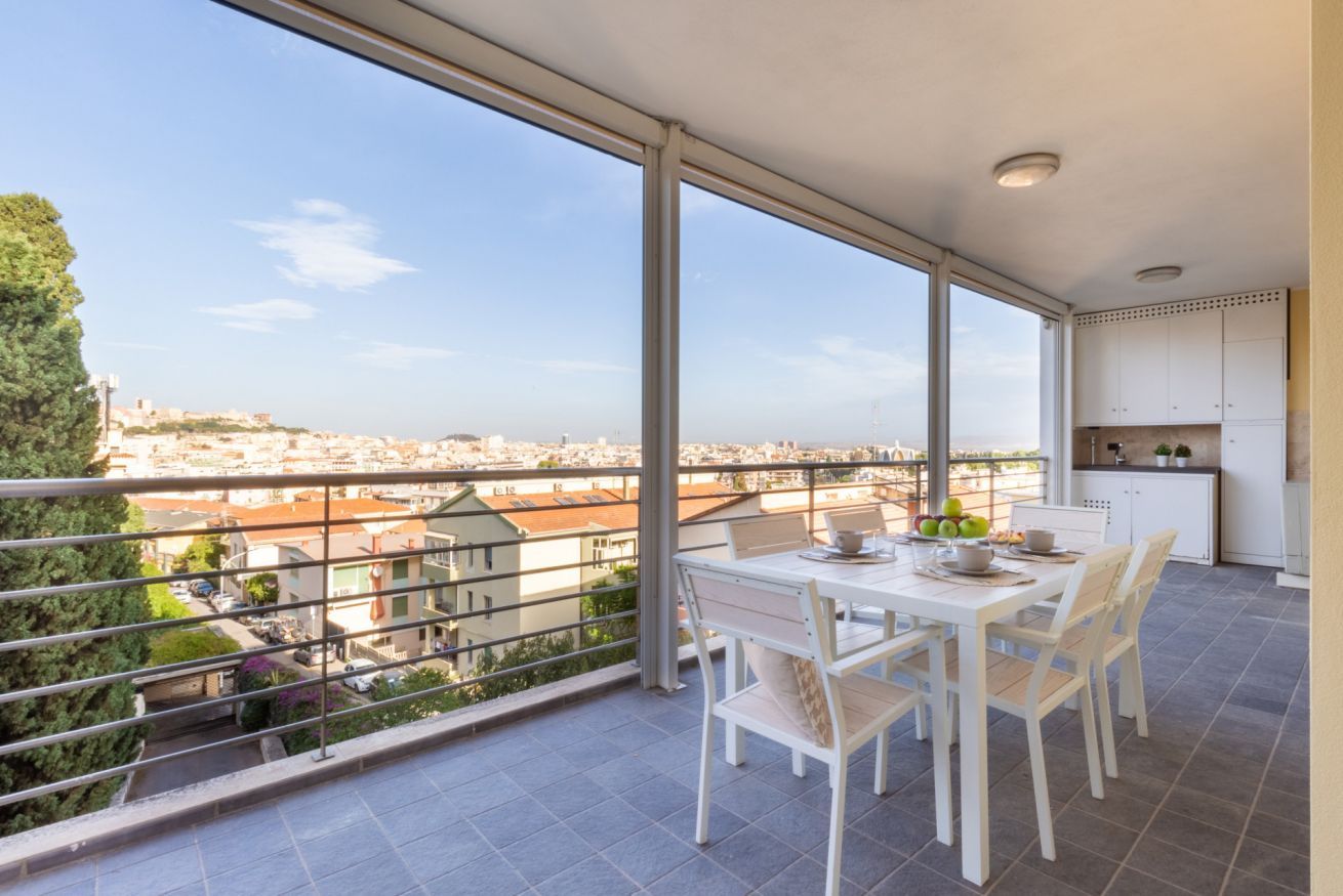 Un balcone con tavolo e sedie, vista sulla città e angolo cottura.