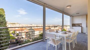 Un balcone con tavolo e sedie, vista sulla città e angolo cottura.