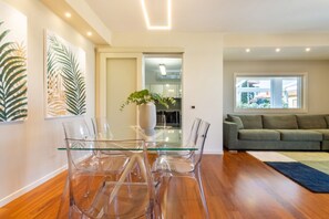 A modern living room with a glass dining table and chairs, a grey sofa, and a large window. - TERRAZZA61 - Apartment with an amazing views of the city of Cagliari (Cagliari)