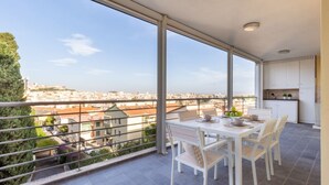 Un balcone con tavolo e sedie, vista sulla città e angolo cottura.