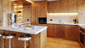 Una cocina moderna con paneles de madera, electrodomésticos de acero inoxidable y una barra con taburetes.
