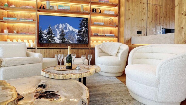 Una sala de estar acogedora con un panel de madera decorativo, asientos cómodos y un televisor grande.