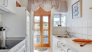 A modern kitchen with white cabinets, a stainless steel stove, and a wooden door leading to an outdoor area. - "Ingebritt" - 1.5km from the sea by Interhome (Blokhus)