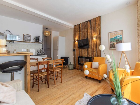 Una sala de estar moderna con una pared de acento de madera, una chimenea y un comedor con sillas y una mesa de madera.