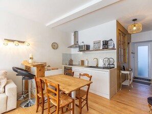 Eine kleine Küche mit Holztisch und -stühlen, einem kleinen Barhocker und einer Uhr an der Wand.