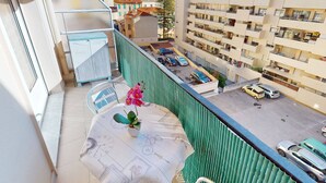 Un balcón con vista a una zona residencial, que incluye coches aparcados y un edificio con varios balcones.