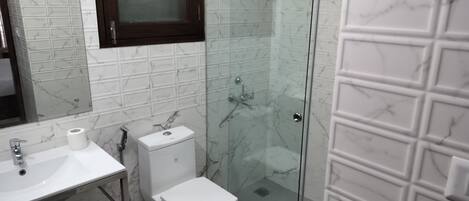 A bathroom with a toilet, sink, and shower area.