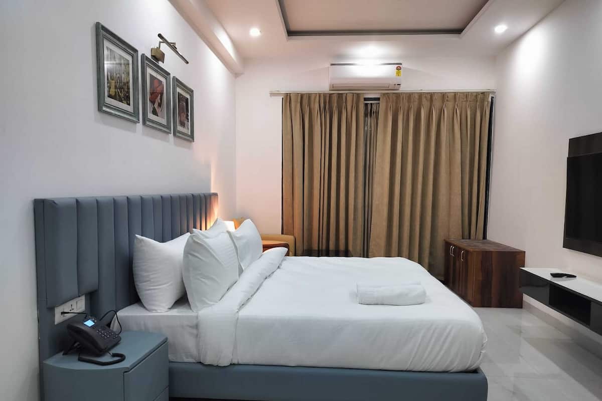 A modern hotel room with a bed, bedside phone, and a TV.