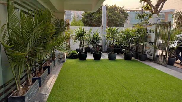 A courtyard with artificial grass, potted plants, and a gated entrance. - The Hoften Elite 32 Avenue, Sector 15, Gurugram (Gurugram)