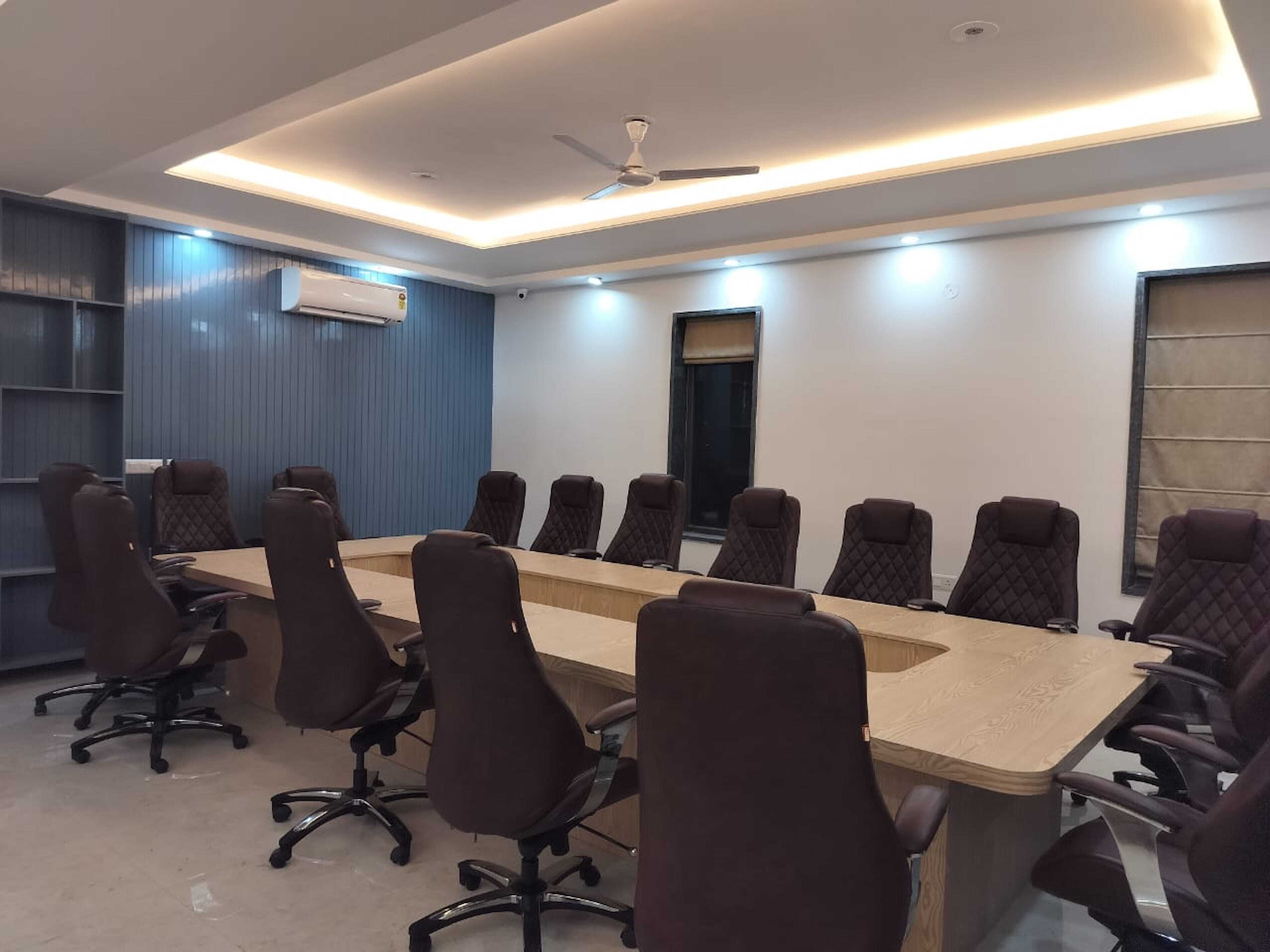 A conference room with a long table and multiple chairs, a ceiling fan, and an air conditioning unit.
