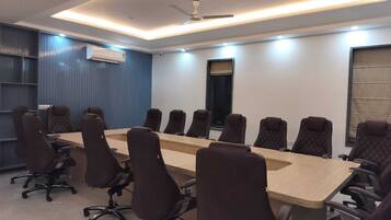 A conference room with a long table and multiple chairs, a ceiling fan, and an air conditioning unit.
