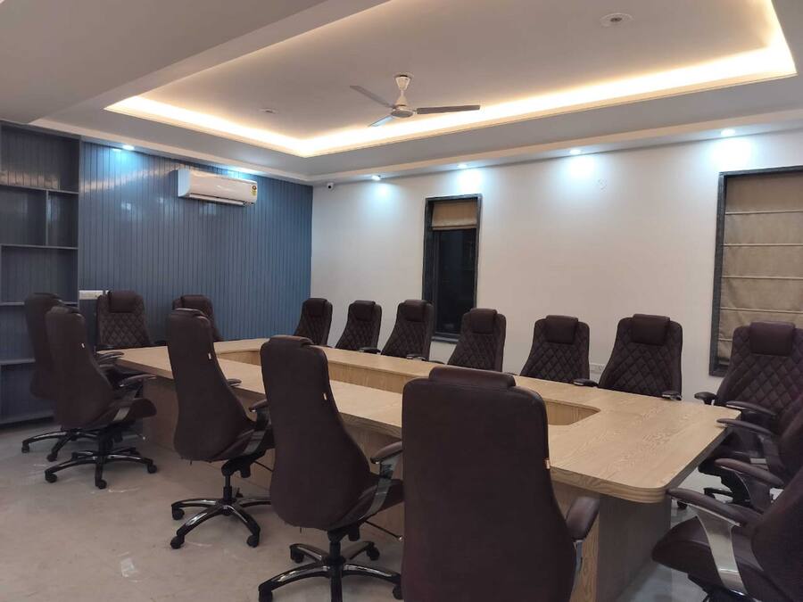 A conference room with a long table and multiple chairs, a ceiling fan, and an air conditioning unit.