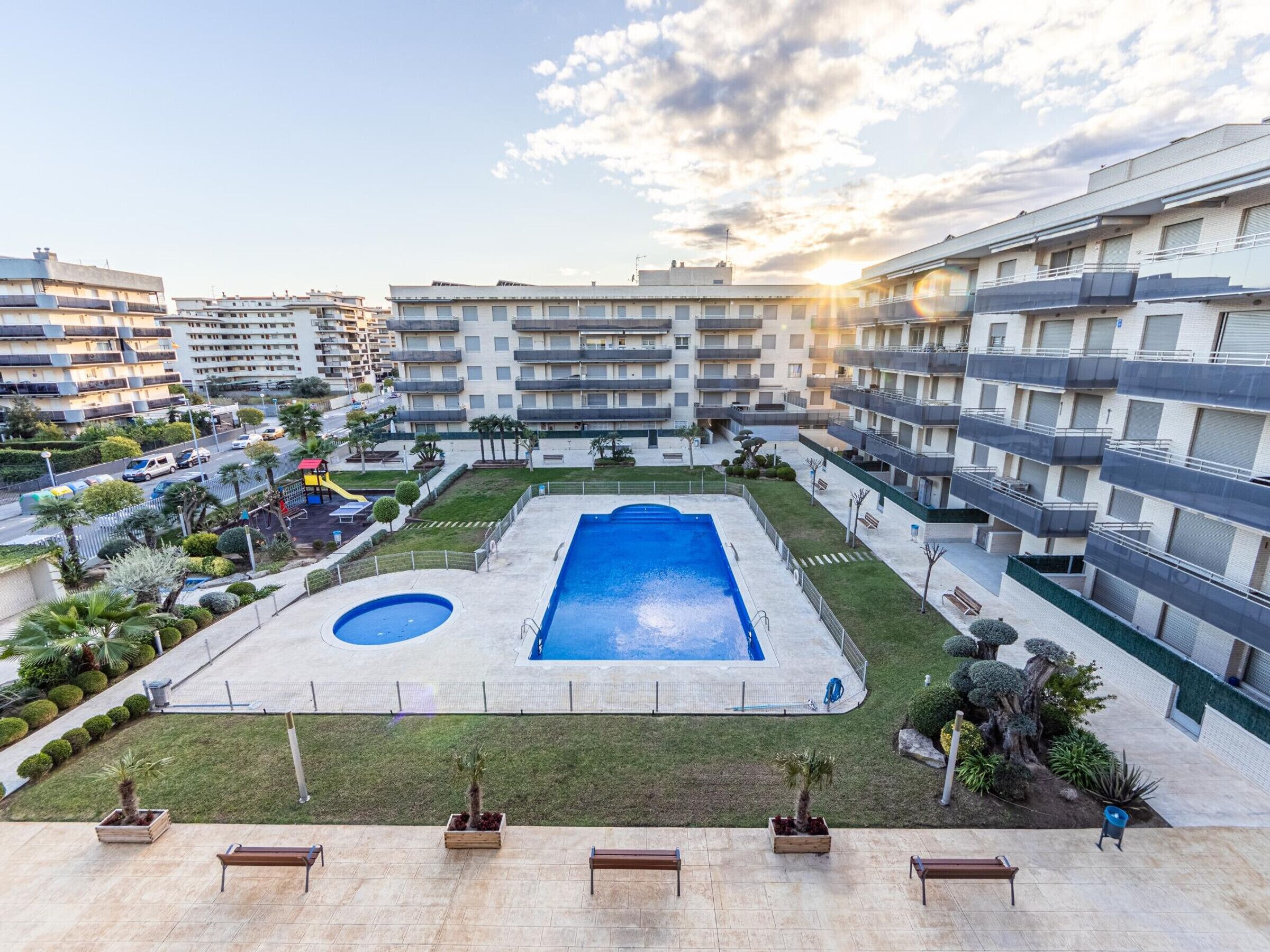 A residential building with multiple balconies, a swimming pool, and a well-maintained garden area.