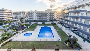 Un edificio residenziale con diversi balconi, una piscina e un giardino curato.