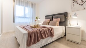 Camera da letto moderna con un letto grande, lampade sui comodini e un quadro appeso al muro.