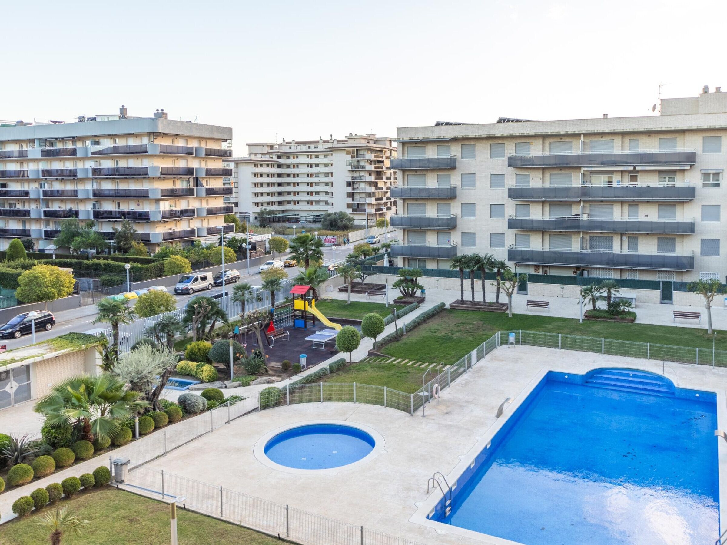 A residential area with a swimming pool, a playground, and multi-story apartment buildings.