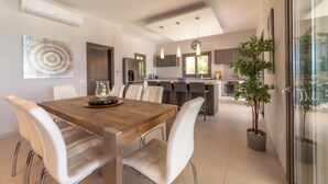 Una cocina moderna con una isla central, sillas blancas y una mesa de comedor.