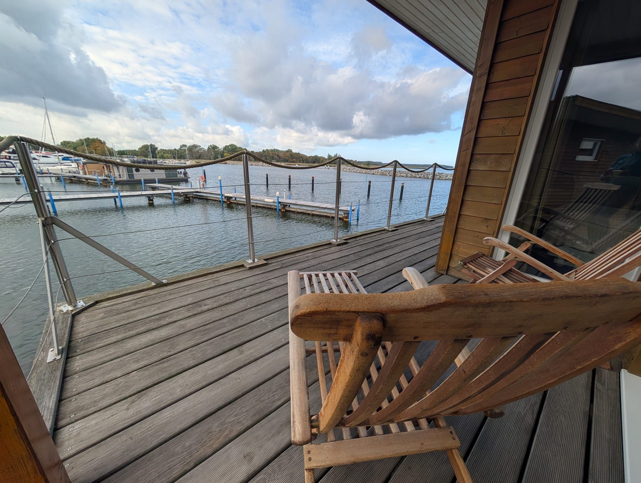 A wooden deck with a view of a marina and boats.
