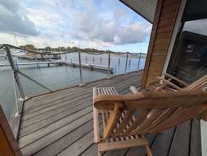 Una terraza de madera con vistas a un puerto deportivo y barcos.