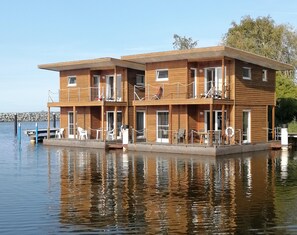 Un edificio de madera de varios pisos con balcones, ubicado sobre una masa de agua.