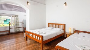 Un dormitorio ordenado con una cama de madera, una mesita de noche con una lámpara y una ventana con vistas a zonas verdes.