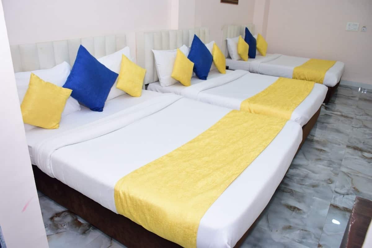 A hotel room with four beds arranged in a row, each with white bedding and yellow accents.