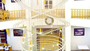 Un atrium à plusieurs niveaux, agrémenté d’un imposant lustre, d’un escalier en colimaçon et d’un balcon doté de rampes dorées.