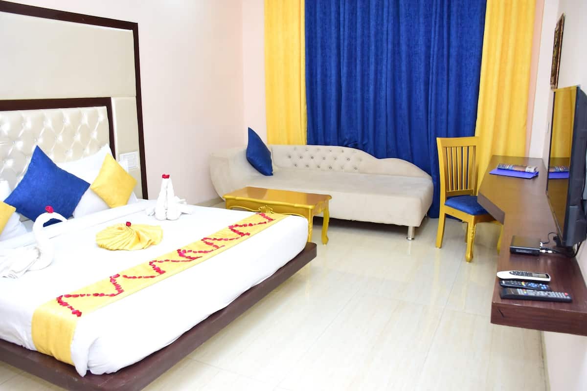 A hotel room with a bed, a sofa, a small table, a TV, and a chair.
