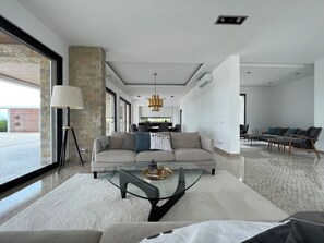 A modern living room with a sofa, coffee table, and a dining area in the background.