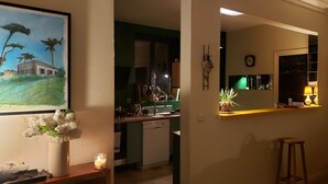 A kitchen with a sink, countertop, and a potted plant. There is a painting on the wall and a candle on a table. - Havre de Paix (Montreuil)
