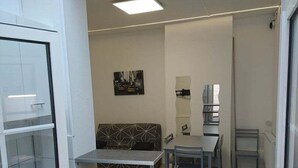 Ein moderner Büroraum mit Glastrennwand, einer Couch, einem Tisch mit Stühlen und einem Bild an der Wand.