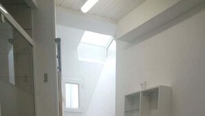 Ein kleiner, schmaler Raum mit Dusche, Waschbecken und Fenster.