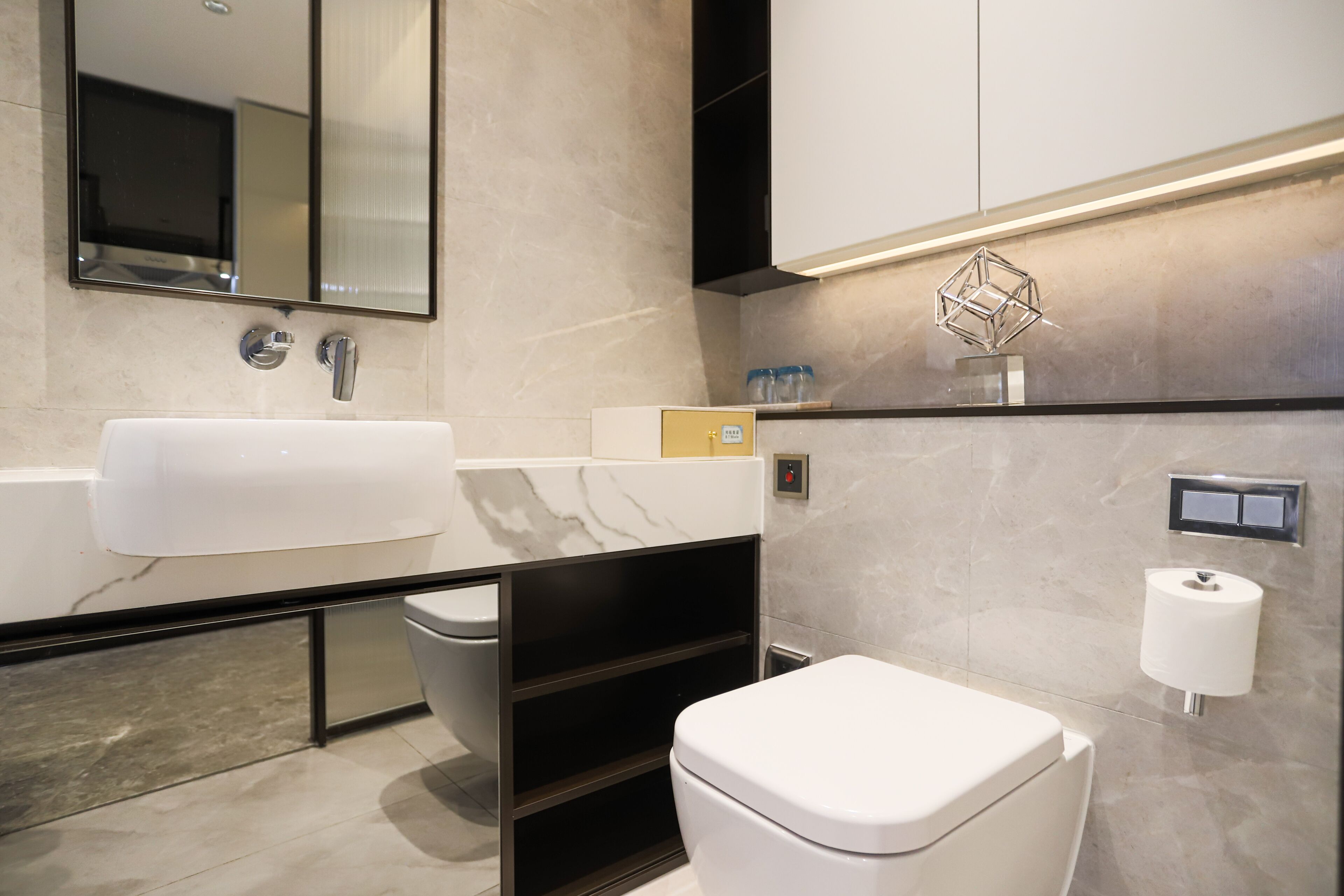 A modern bathroom with a white sink, a toilet, and a mirror.
