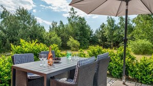 An outdoor patio with a table, chairs, and an umbrella.