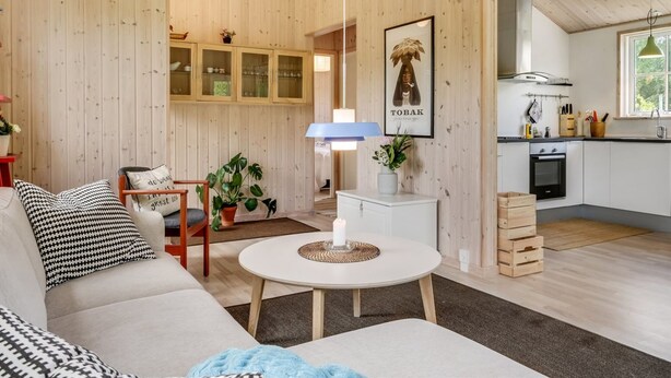 A cozy living room with a sofa, a round table, and a kitchen area with cabinets and a stove.