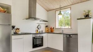 A modern kitchen with white cabinets, a built-in oven, a dishwasher, and a window with natural light.