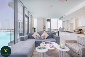 Enjoy a panoramic view of the city and water from this spacious living area, featuring a comfortable sofa and dining space.