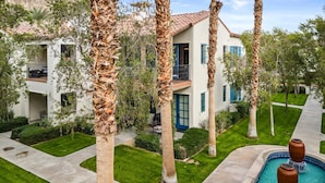 A multi-story building with a pool, surrounded by palm trees and well-maintained lawns. - LV031 Luxurious Upstairs Legacy Villas Studio (La Quinta)