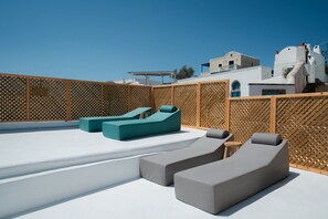 A rooftop terrace with modern lounge chairs and a wooden lattice fence. - Marla Luxury Residences (Santorini)
