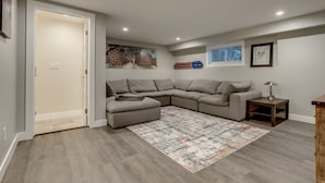 A modern living room with a sectional sofa, a rug, and artwork on the walls.