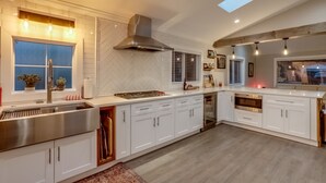 A modern kitchen with white cabinetry, a stainless steel sink, a built-in oven, and a skylight.