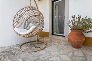 A wicker chair with cushions, a potted plant, and a stone-tiled floor. - Quinta dos Pinheiros Mansos - Serra d'Arrábida (Azeitão)