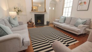 A living room with two sofas, a fireplace, a striped rug, and a large mirror. - Scillonia (Penzance)