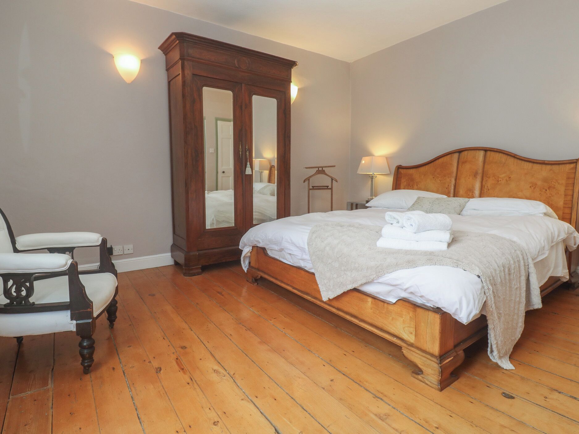 Een slaapkamer met een houten bed, een nachtkastje, een dressoir en een stoel.