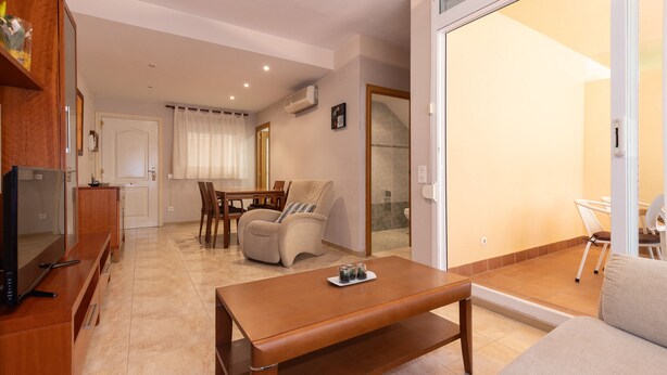 A modern living room with a wooden coffee table, a sofa, and a dining area with chairs and a table. - Ground floor duplex large terrace UHC GOLDEN PINEDA APARTMENTS 206 (La Pineda)