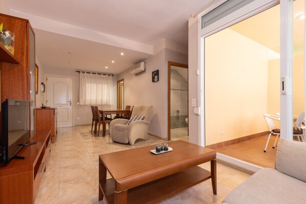 A modern living room with a wooden coffee table, a sofa, and a dining area with chairs and a table. - Ground floor duplex large terrace UHC GOLDEN PINEDA APARTMENTS 206 (La Pineda)