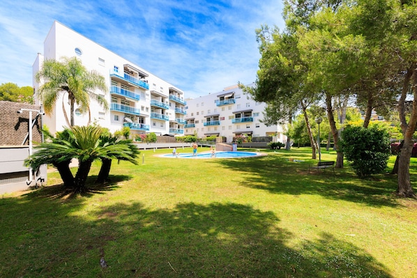 A modern building with multiple balconies, a swimming pool, and a well-maintained lawn with trees. - Ground floor duplex large terrace UHC GOLDEN PINEDA APARTMENTS 206 (La Pineda)